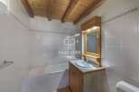 Discover this charming bathroom featuring a wooden ceiling and a stylish vanity.