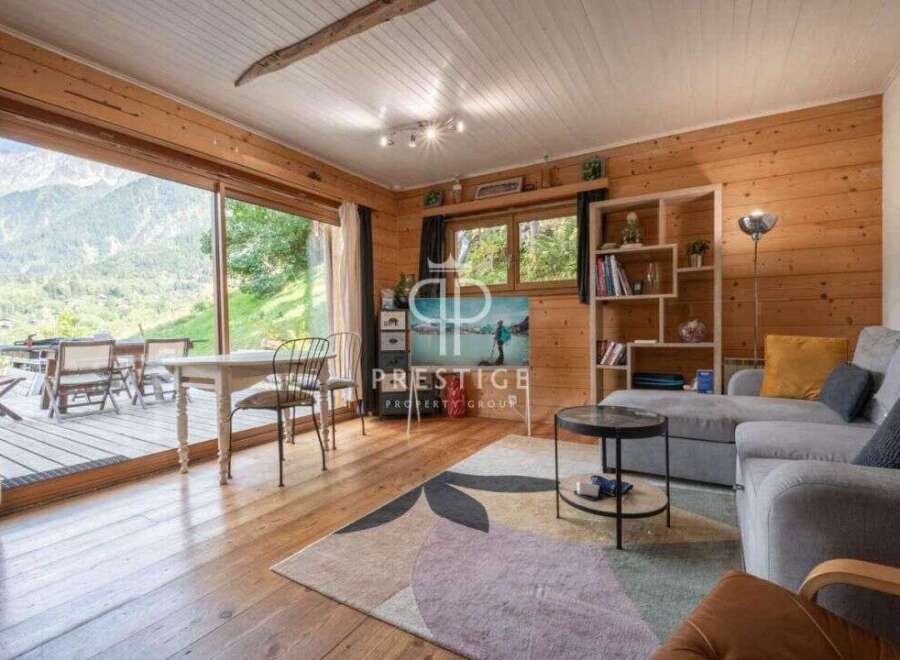 Experience the charm of this stunning property, featuring a cozy living room with wooden walls and a breathtaking mountain view.