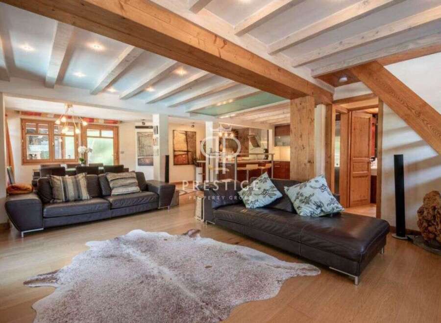 Experience luxury living in this stunning property, featuring a spacious living area with exposed wooden beams and a cozy fireplace.