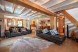Experience luxury living in this stunning property, featuring a spacious living area with exposed wooden beams and a cozy fireplace.