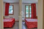 Discover a charming property featuring two cozy bedrooms, each adorned with vibrant red curtains and comfortable beds.