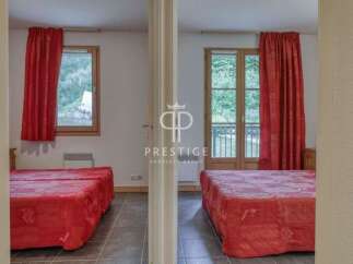 Discover a charming property featuring two cozy bedrooms, each adorned with vibrant red curtains and comfortable beds.