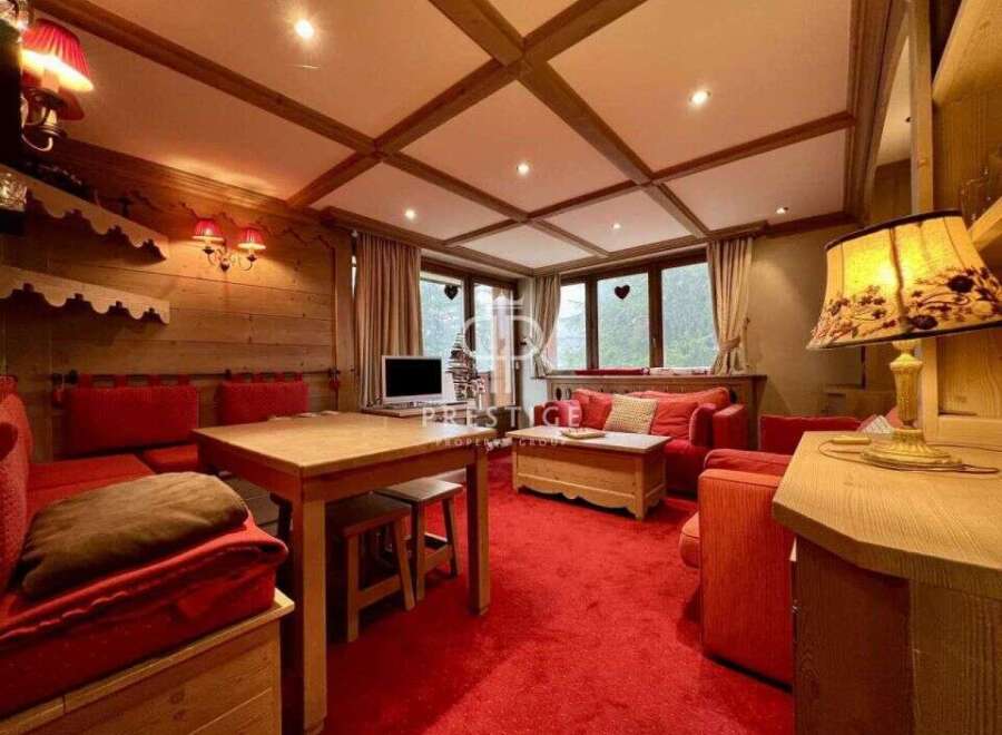 Experience the warmth of this charming property, featuring a cozy living space with a red carpet and wooden accents.