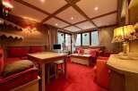 Experience the warmth of this charming property, featuring a cozy living space with a red carpet and wooden accents.