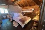 Experience rustic charm in this cozy bedroom, featuring warm wooden accents and a unique sloped ceiling.