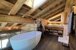 Experience luxury in this stunning property featuring a unique wooden ceiling and a modern bathtub.