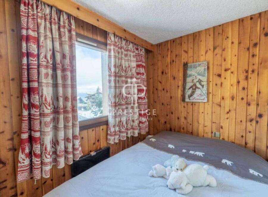 Cozy bedroom with wooden paneling and charming curtains.