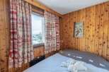 Cozy bedroom with wooden paneling and charming curtains.