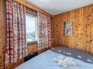 Cozy bedroom with wooden paneling and charming curtains.