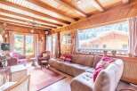Experience the charm of this stunning property, featuring a cozy living room with a wooden ceiling and large windows.