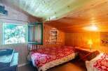 Cozy cabin bedroom with wooden walls and ceiling.