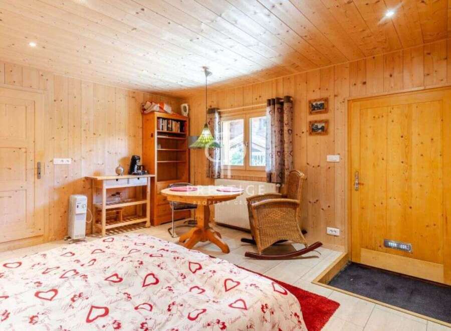 Cozy chalet bedroom with wooden walls and ceiling, creating a warm and inviting atmosphere.
