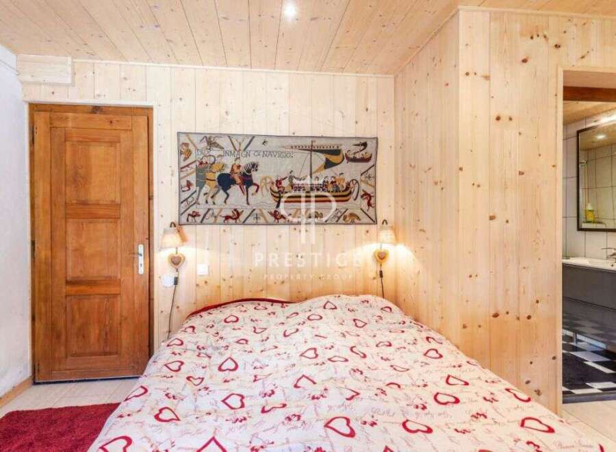 Cozy bedroom with wooden walls and ceiling, creating a warm and inviting atmosphere.