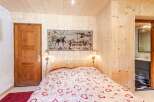 Cozy bedroom with wooden walls and ceiling, creating a warm and inviting atmosphere.