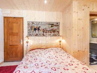 Cozy bedroom with wooden walls and ceiling, creating a warm and inviting atmosphere.