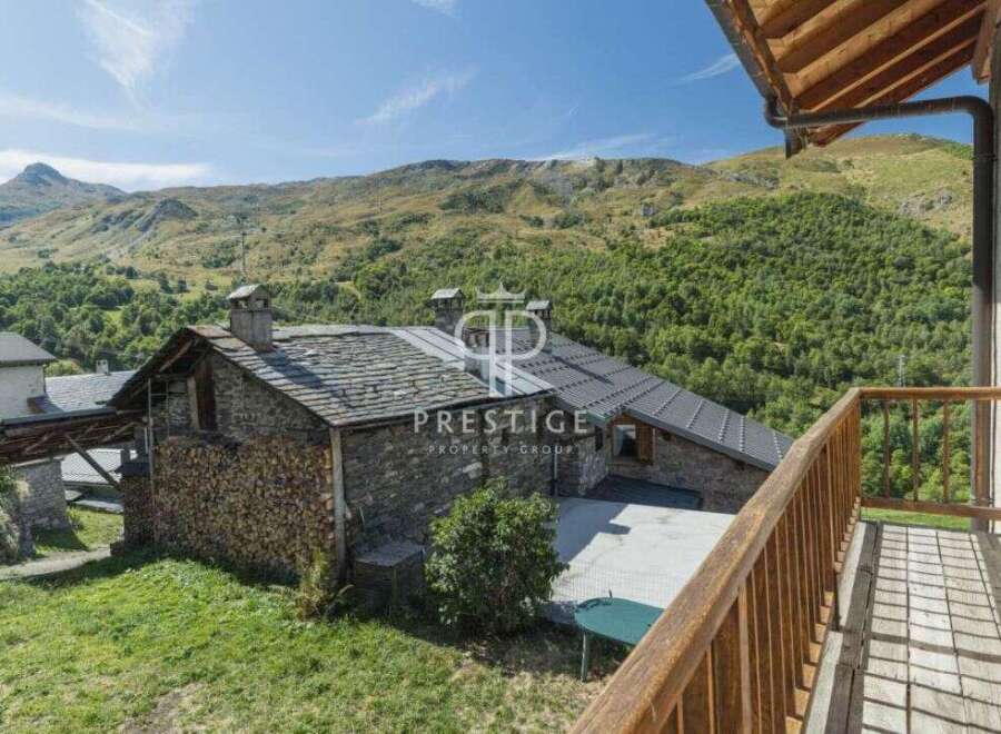 Discover a charming stone house nestled in a picturesque mountain setting.