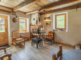 Discover the charm of this rustic property, featuring a cozy living room with a fireplace and wooden beams.