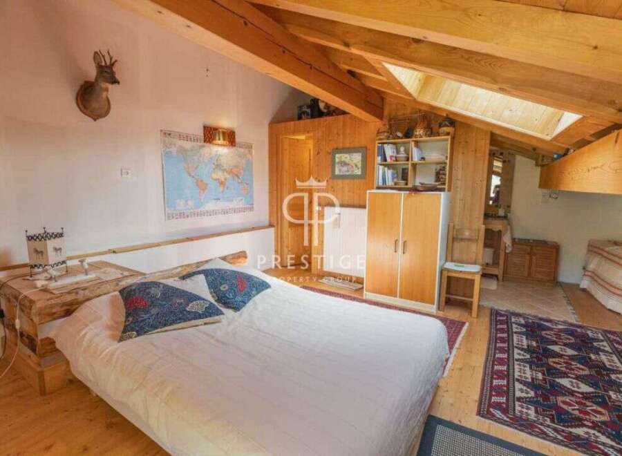 Discover a cozy bedroom with a rustic charm, featuring exposed wooden beams and a comfortable bed.