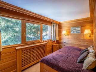 Experience the warmth of this cozy bedroom, featuring stunning wooden paneling and a serene ambiance.