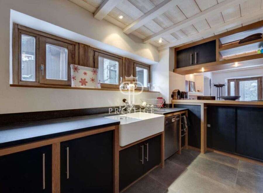 Discover the charm of this rustic kitchen, featuring a farmhouse sink and sleek black cabinetry.