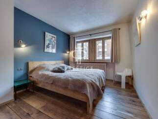 Cozy bedroom with a rustic wooden floor and a comfortable bed.