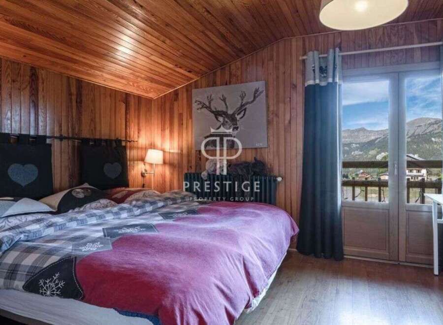 Cozy bedroom with wooden walls and ceiling, creating a warm and inviting atmosphere.