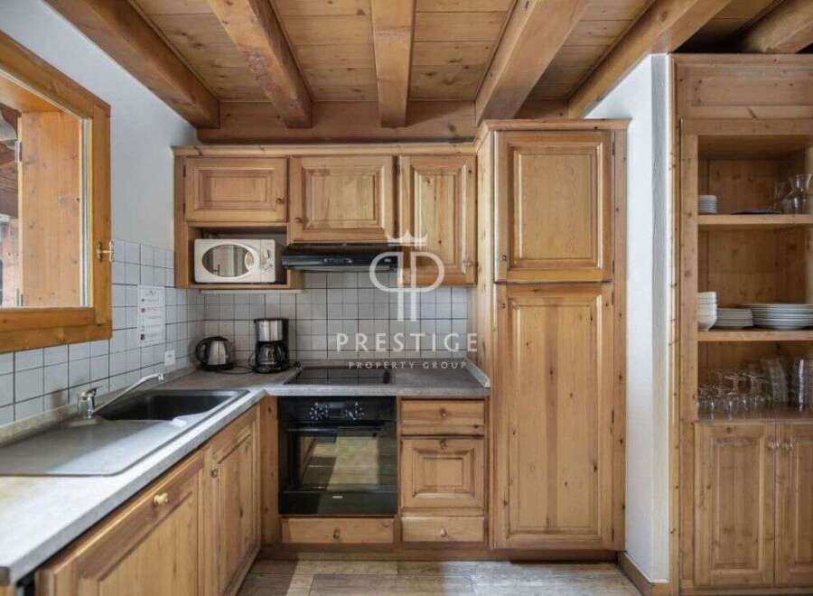 Discover the charm of this cozy kitchen, featuring warm wooden cabinetry and a rustic ceiling.