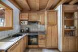 Discover the charm of this cozy kitchen, featuring warm wooden cabinetry and a rustic ceiling.