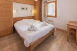 Discover the charm of this cozy bedroom, featuring a warm wooden interior and a comfortable bed.