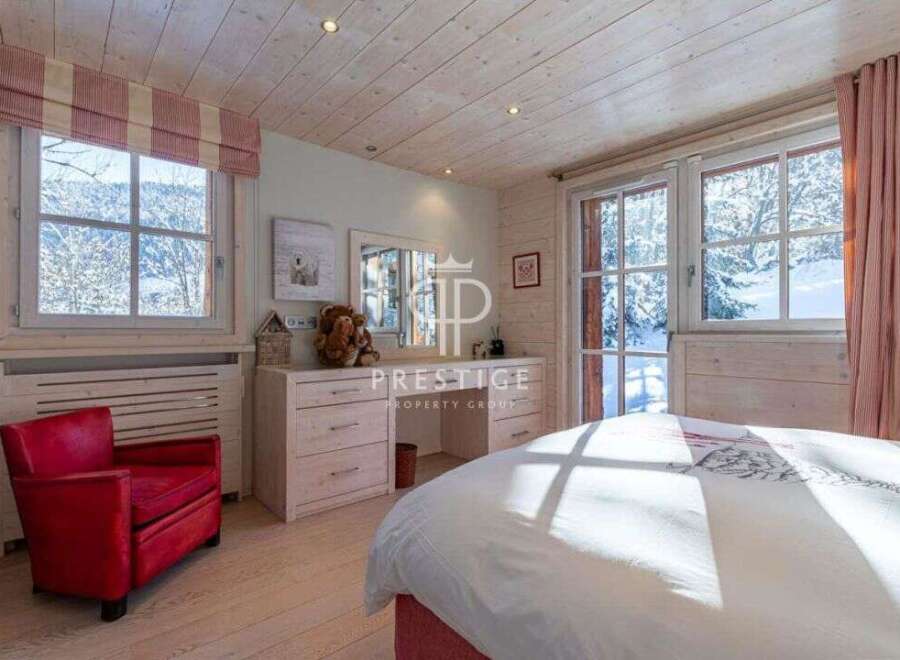 Experience the charm of this cozy bedroom, featuring a stunning view of a snowy landscape through large windows.
