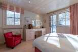 Experience the charm of this cozy bedroom, featuring a stunning view of a snowy landscape through large windows.