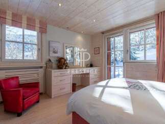 Experience the charm of this cozy bedroom, featuring a stunning view of a snowy landscape through large windows.