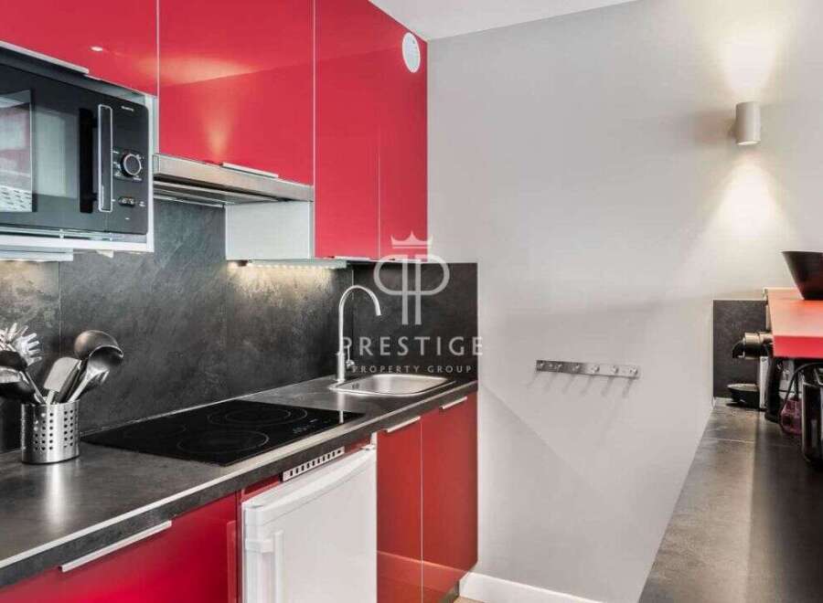 Modern kitchen with sleek red cabinets and a built-in microwave.