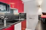 Modern kitchen with sleek red cabinets and a built-in microwave.