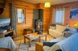 Cozy up in this charming cabin! Featuring a warm wooden interior, a fireplace, and comfortable seating, this space is perfect for relaxation.
