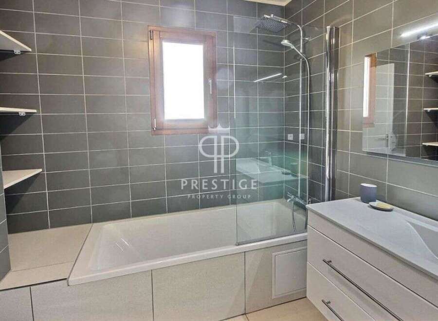 Discover a modern bathroom with sleek gray tiles and a luxurious bathtub.