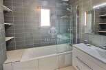 Discover a modern bathroom with sleek gray tiles and a luxurious bathtub.