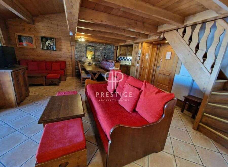 Discover the charm of this cozy property, featuring a warm wooden interior and inviting red sofas.