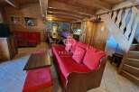 Discover the charm of this cozy property, featuring a warm wooden interior and inviting red sofas.