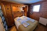 Cozy bedroom with wooden paneling and a built-in wardrobe.