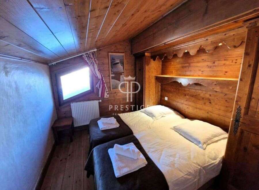 Cozy chalet bedroom featuring warm wooden accents and a charming, sloped ceiling.