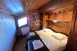 Cozy chalet bedroom featuring warm wooden accents and a charming, sloped ceiling.