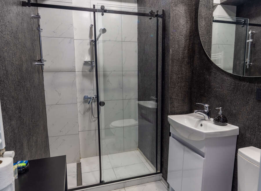 This modern bathroom features a sleek shower with a glass door, complemented by stylish white tiles.