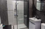 This modern bathroom features a sleek shower with a glass door, complemented by stylish white tiles.