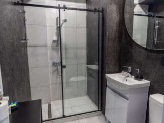 This modern bathroom features a sleek shower with a glass door, complemented by stylish white tiles.
