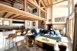 This stunning chalet boasts a spacious open-plan living area with high ceilings and exposed wooden beams, creating a warm and inviting atmosphere.