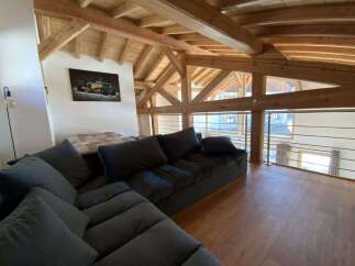Relax in this stunning chalet featuring a spacious open-plan living area with a comfortable sectional sofa and breathtaking views.