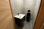 Modern bathroom with black toilet and vanity, and gray stone tile.