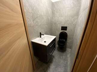 Modern bathroom with black toilet and vanity, and gray stone tile.