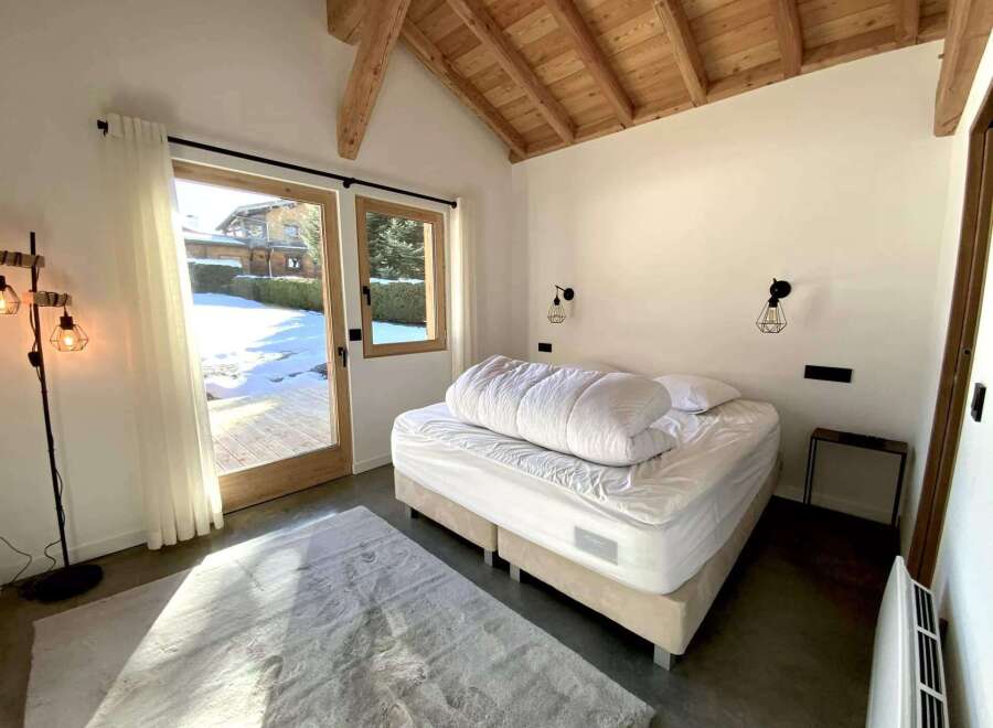 This stunning bedroom boasts a cozy and modern design, featuring a comfortable bed with crisp white linens and a plush duvet.